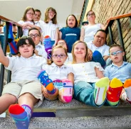 Grupo de niños sentados sonriendo, mostrando sus medias de diferentes colores