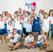 Grupo de niños vestidos de blanco sonriendo y detrás de ellos logo de Red Point 